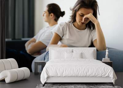 Beautiful young couple is having a quarrel while sitting on sofa at home Wall mural